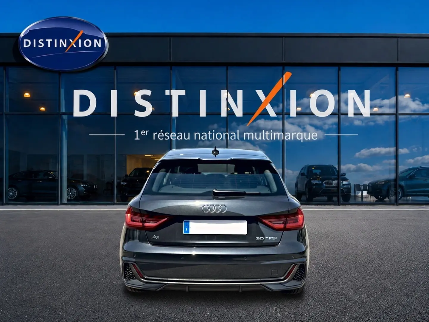 Vue arrière d'une Audi A1 Sportback noire 30 TFSI S line devant une vitrine Distinxion.
