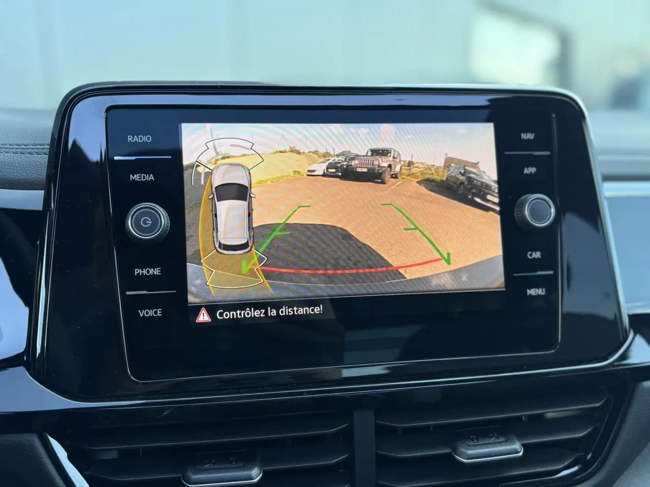 Écran tactile intérieur du Volkswagen T-Roc affichant la caméra de recul avec alertes de distance active.
