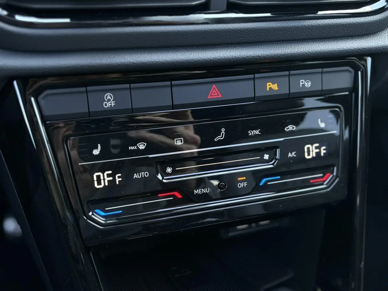 Gros plan sur la commande de climatisation automatique du Volkswagen T-Roc 2025 avec affichage digital et boutons tactiles noirs.