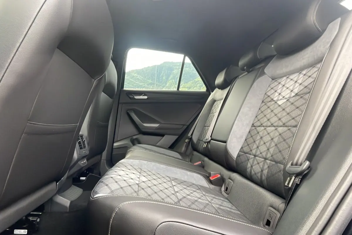 Vue intérieure arrière du Volkswagen T-Roc 2025, sièges arrière en cuir noir et tissu gris à motif losange.
