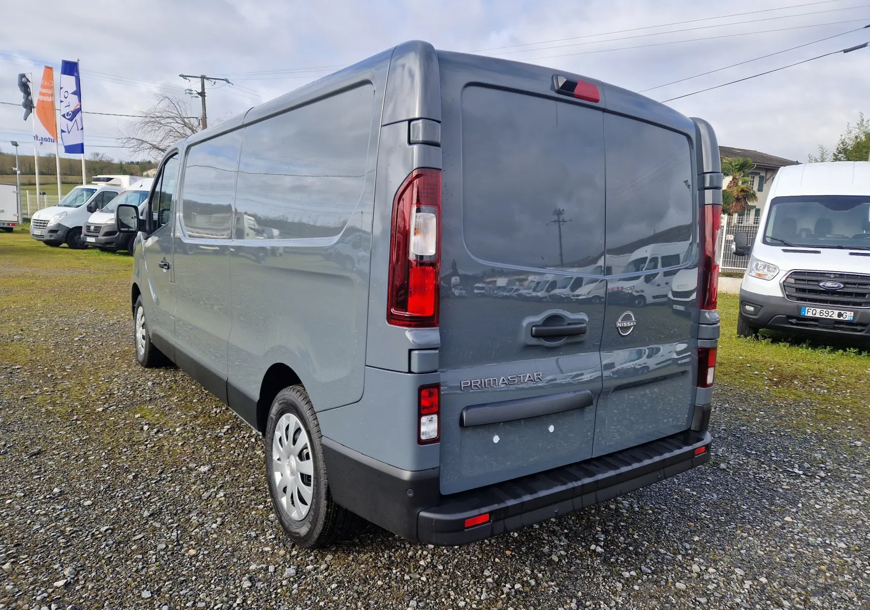 Vue 3/4 arrière droite du Nissan Primastar gris urbain 2025, fourgon utilitaire avec portes arrière pleines.
