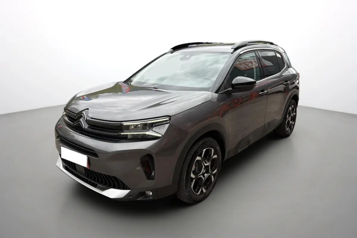 Citroën C5 Aircross gris platinium en 3/4 avant droit, avec barres de toit et jantes alu 18 pouces distinctives.