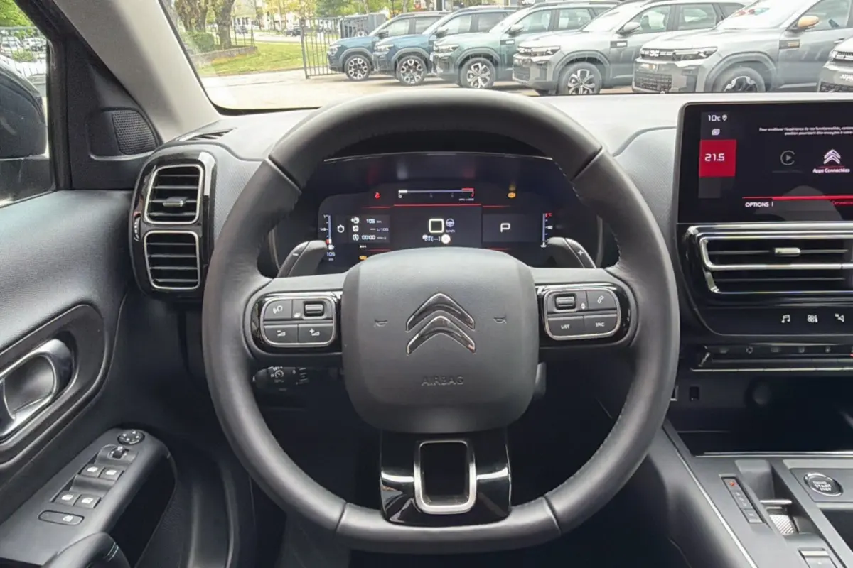 Vue intérieure centrée sur le volant cuir multifonctions d'un Citroën C5 Aircross gris platinium avec tableau de bord digital et écran tactile.
