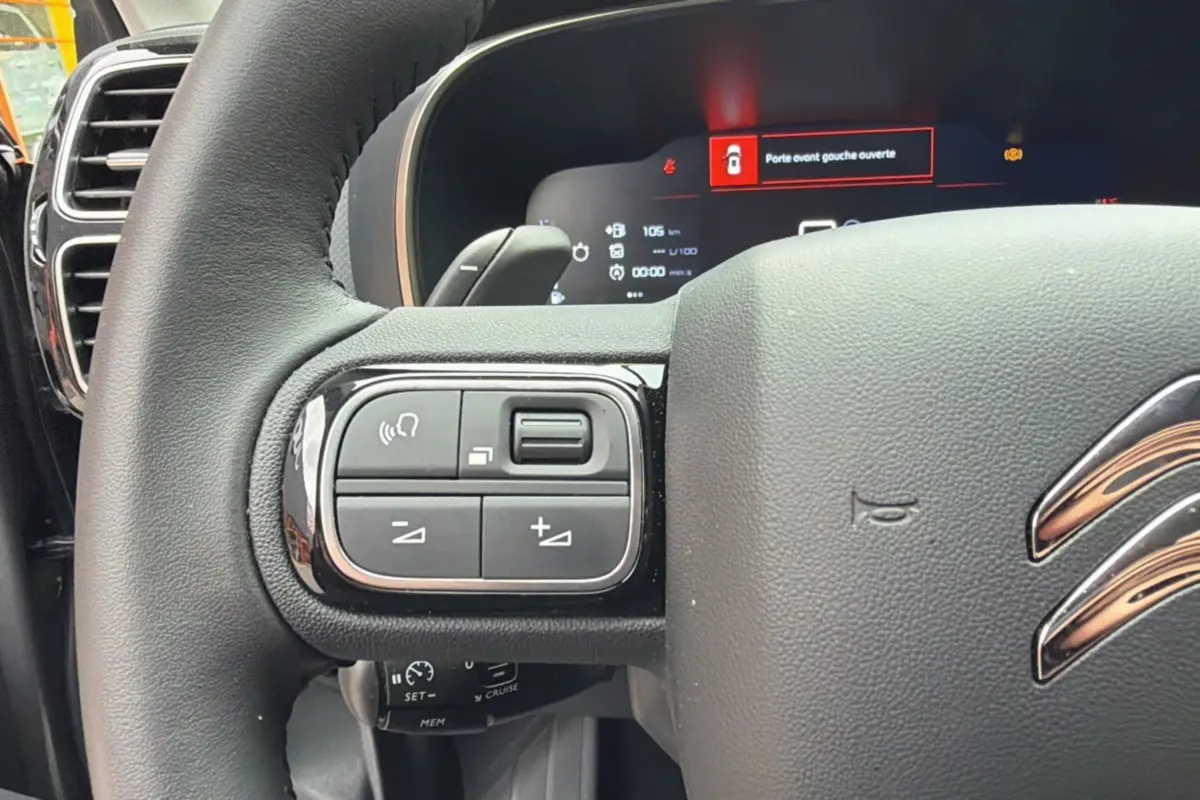 Gros plan sur le volant cuir multifonctions du Citroën C5 Aircross gris platinium, avec commandes intégrées et tableau de bord digital.