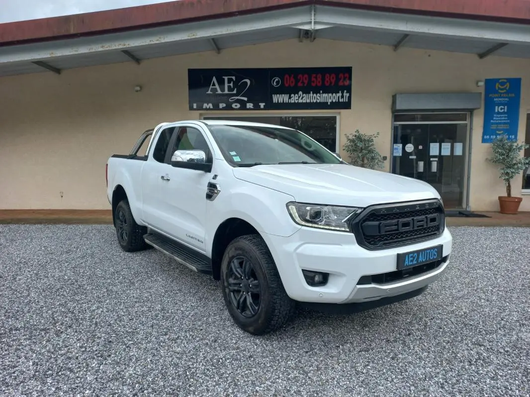 Ford Ranger Super Cabine Limited blanc vu en 3/4 avant droit avec calandre noire et jantes noires sur gravier.