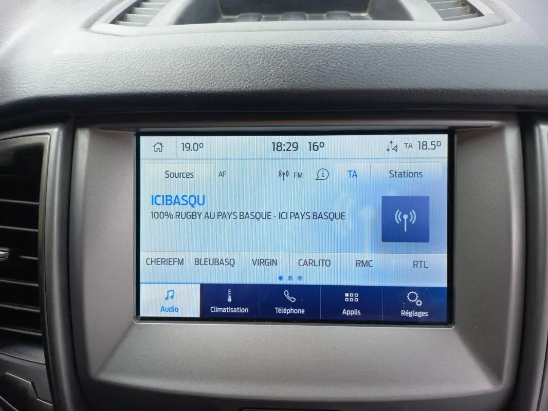 Écran tactile central du Ford Ranger blanc 2022 affichant la radio et les options de climatisation et téléphone.