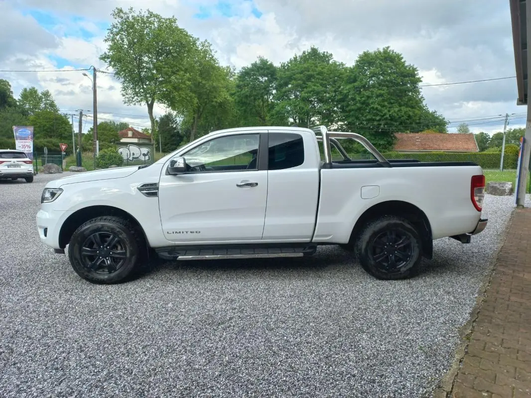 Ford Ranger Super Cabine Limited blanc vu de profil côté gauche, avec barres de protection chromées et jantes noires.