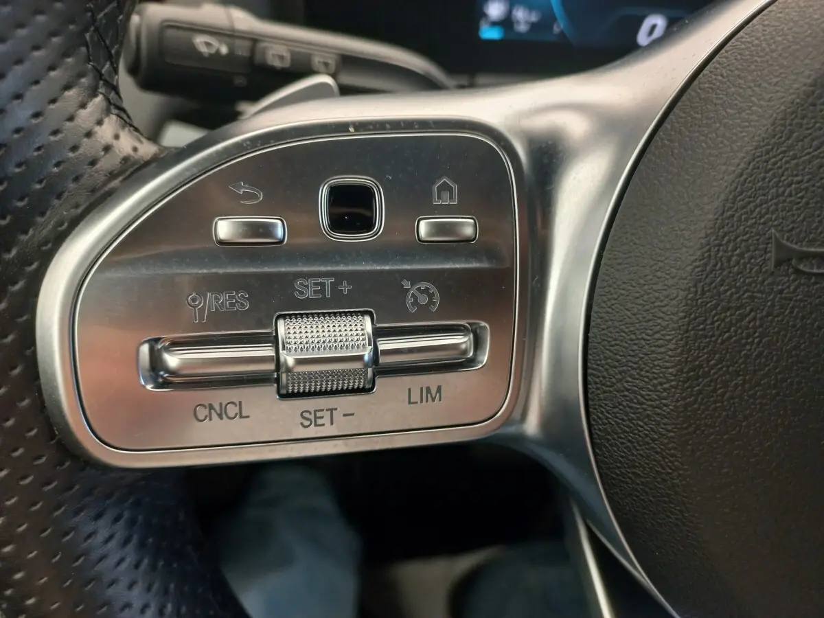 Gros plan sur les commandes argentées du volant côté gauche de la Mercedes Classe A A 200 AMG Line noire.