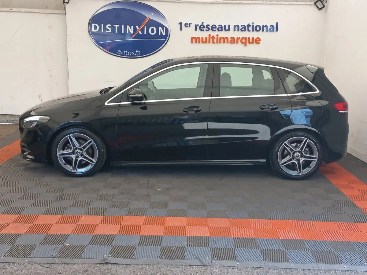 Vue de profil côté gauche d'une Mercedes Classe A berline A 200 AMG Line noire stationnée en intérieur.