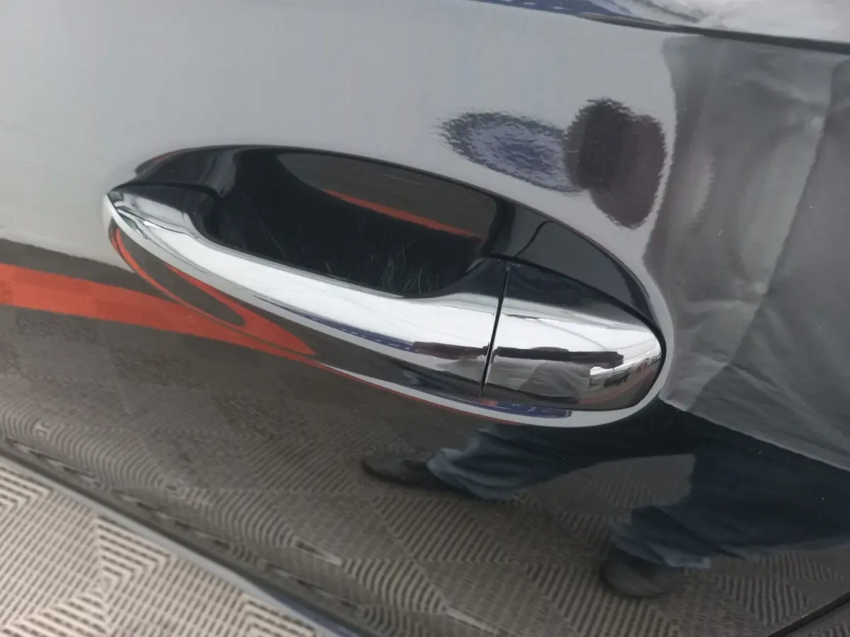 Poignée de porte chromée sur la porte côté droit d'une Mercedes Classe A Berline noire brillante.