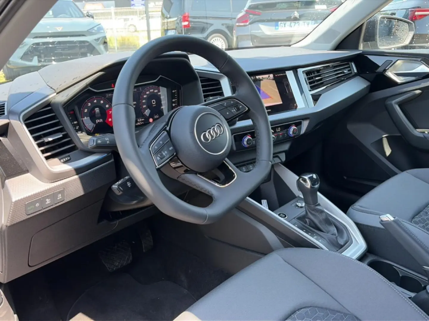 Vue intérieure côté conducteur de l'Audi A1 Sportback 2026, avec volant cuir multifonction et tableau de bord digital.