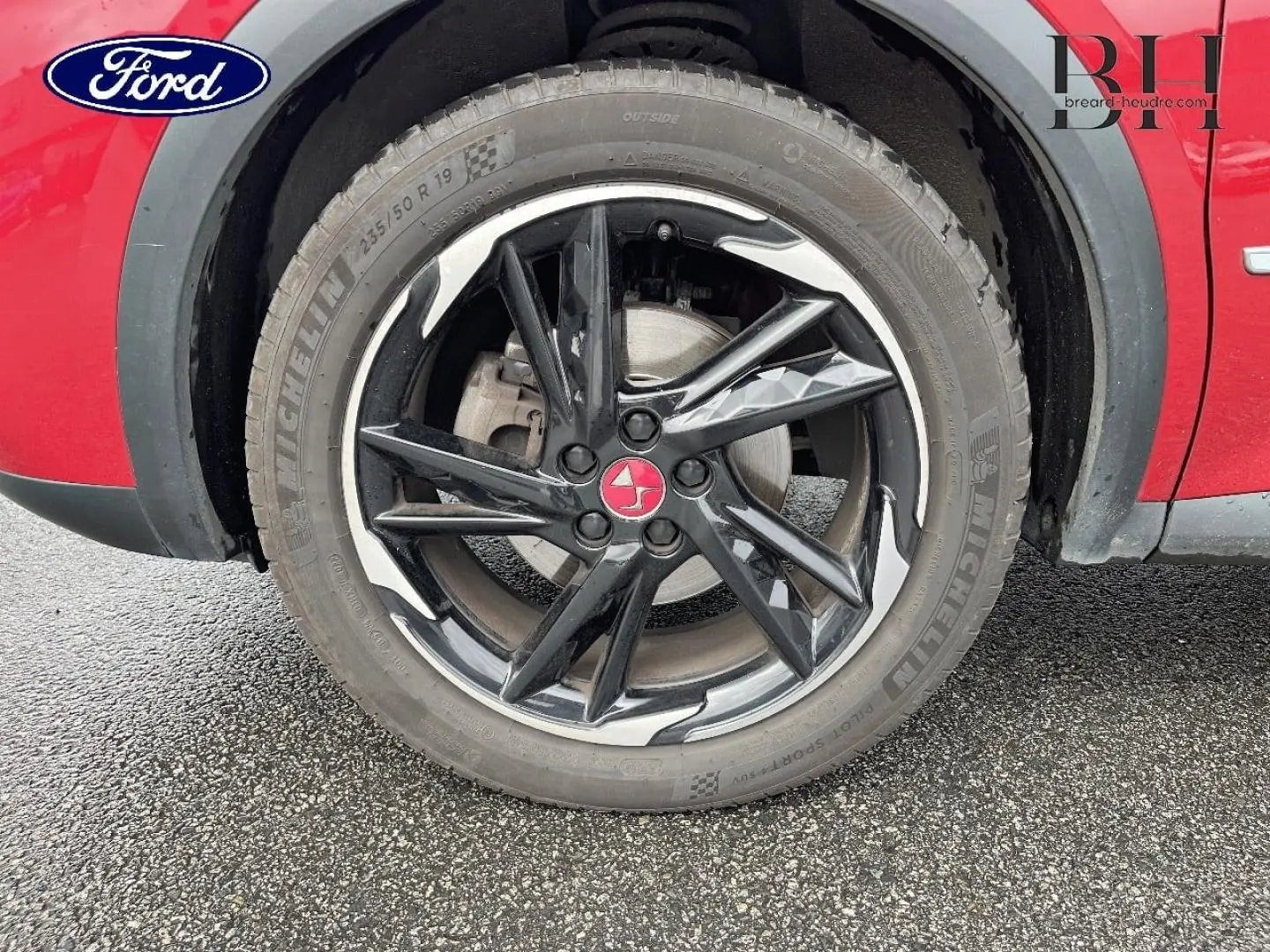 Gros plan sur la roue avant droite noire avec jante diamantée et carrosserie rouge absolu du DS7 Crossback.