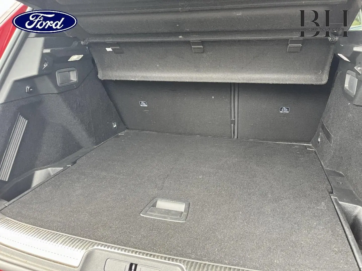 Coffre ouvert d'un DS7 Crossback rouge, vue intérieure montrant un espace de chargement spacieux et tapis noir.