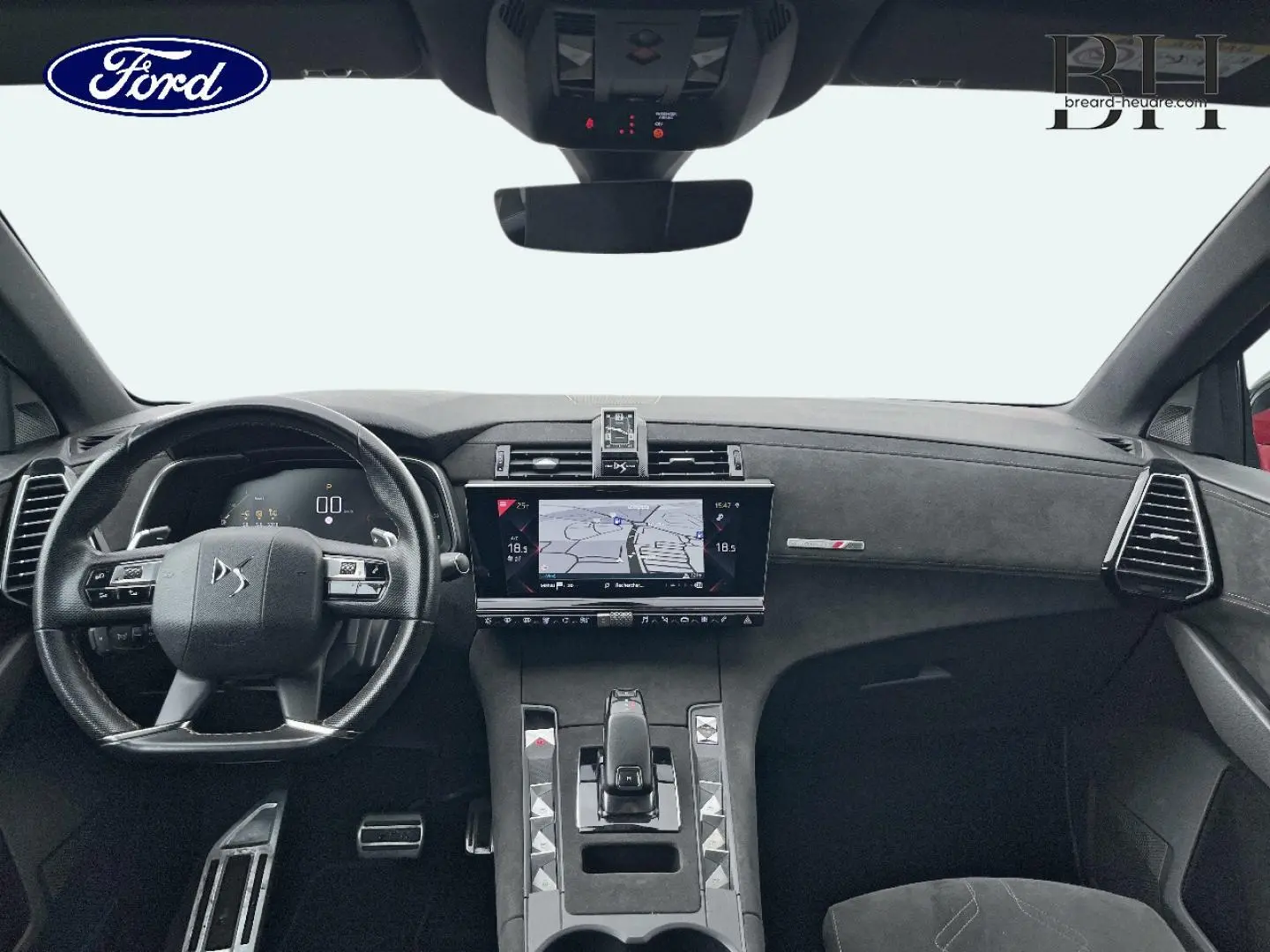 Vue intérieure avant du DS7 Crossback avec tableau de bord noir et écran tactile central affichant la navigation.