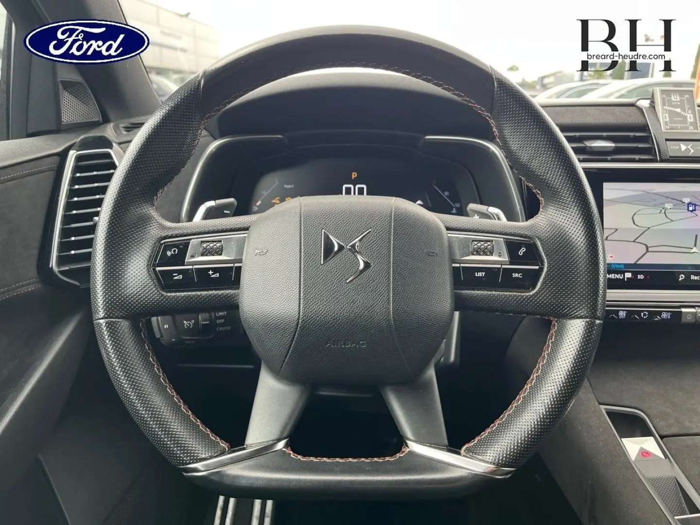 Volant DS en cuir noir avec coutures rouges et tableau de bord numérique d'un DS7 Crossback, vue de face intérieure.