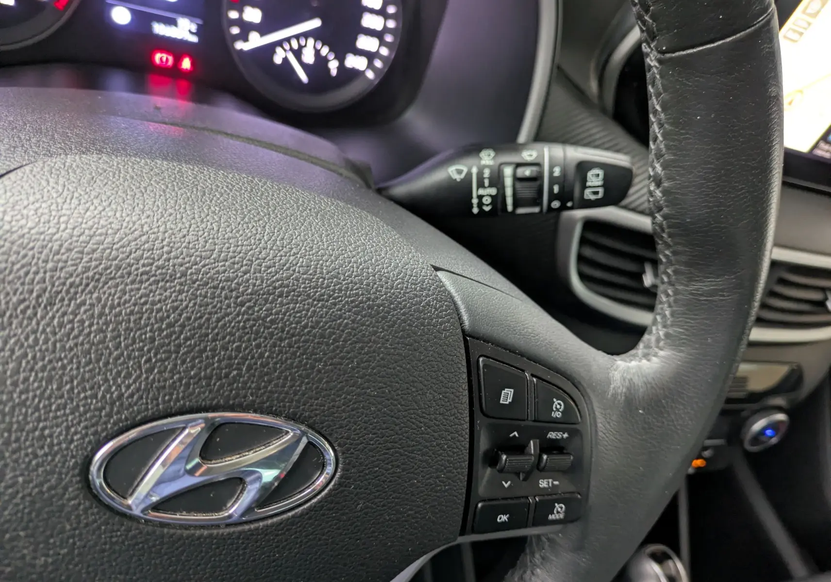 Gros plan sur le volant noir du Hyundai Tucson 2020 avec commandes intégrées et tableau de bord partiellement visible.