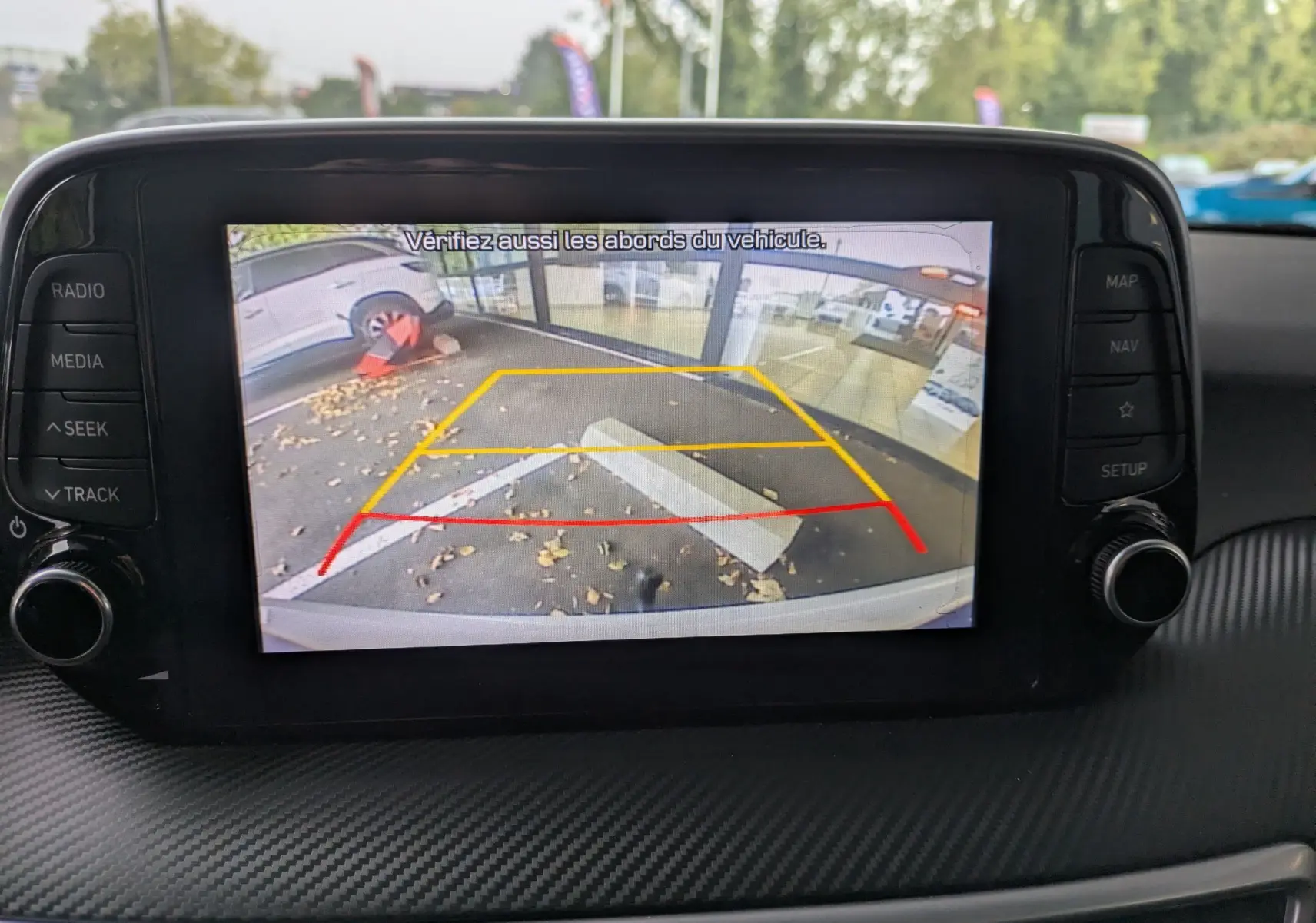 Vue intérieure sur l'écran de la caméra de recul du Hyundai Tucson blanc, affichant les lignes de guidage colorées.
