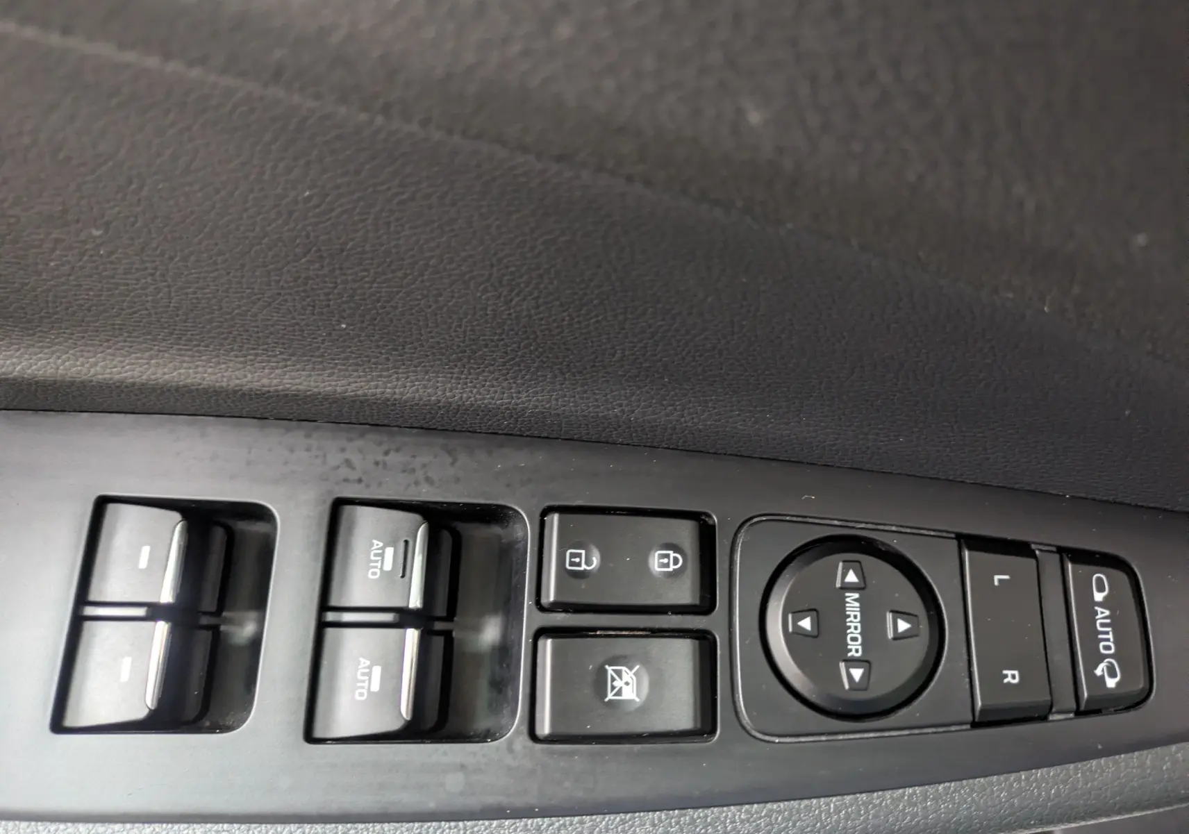 Gros plan sur les commandes de lève-vitres et réglage des rétroviseurs côté conducteur d'un Hyundai Tucson blanc 2020.