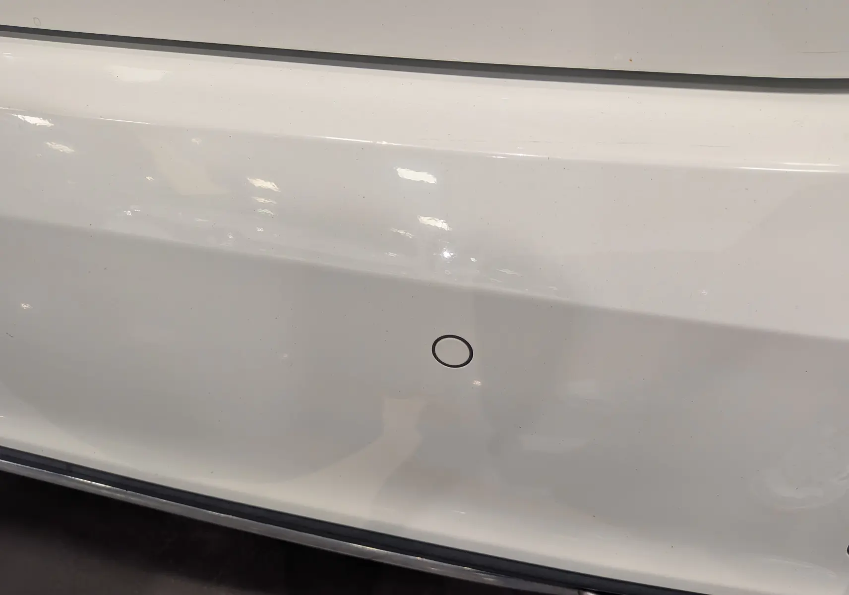 Gros plan sur le pare-chocs arrière blanc d'une Mercedes Classe A 200d 2016 avec capteur de recul visible.