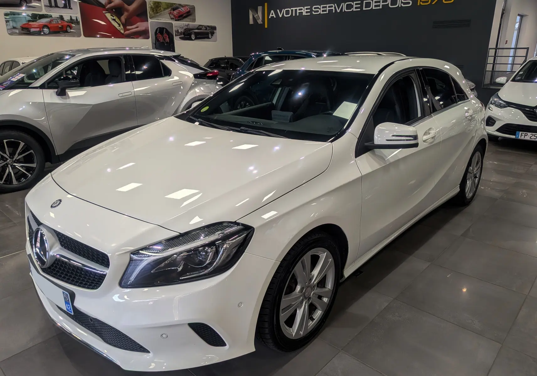 Mercedes Classe A 200d blanc vue 3/4 avant droit en showroom avec jantes alliage et rétroviseurs blancs.