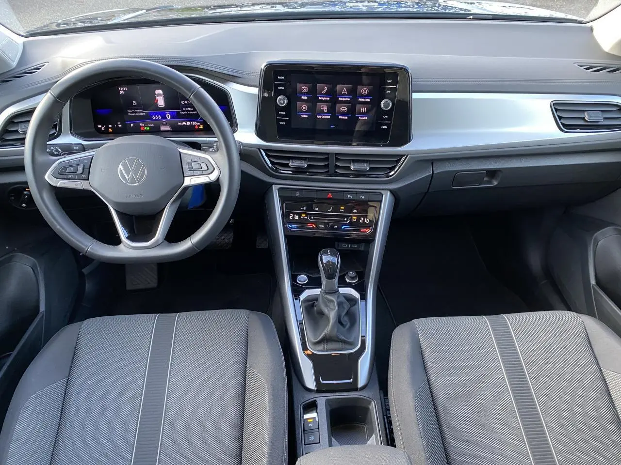 Intérieur du Volkswagen T-Roc 2025 vu de face, tableau de bord noir avec écran tactile et volant multifonction.