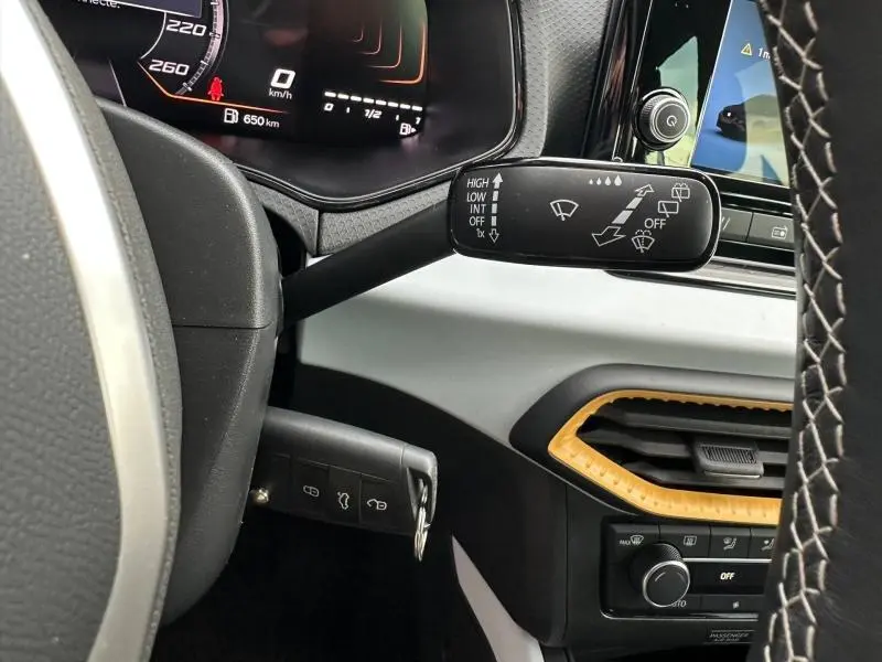 Vue intérieure côté gauche du tableau de bord du SEAT Arona 2025, avec commandes d’essuie-glace et détails jaunes autour de la sortie d’air.