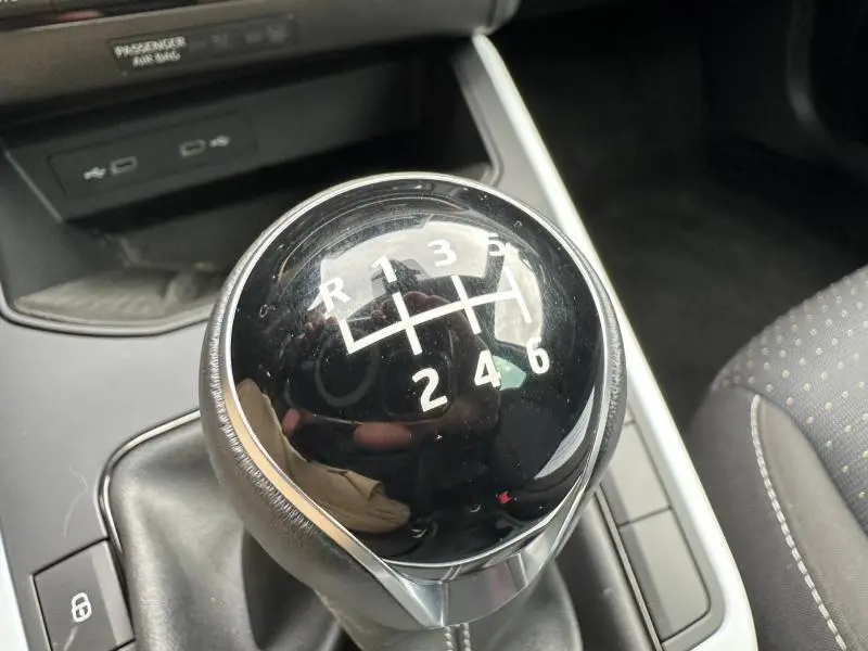 Le levier de vitesse manuel noir brillant du SEAT Arona 2025, avec marquages blancs des rapports, vu en gros plan intérieur.