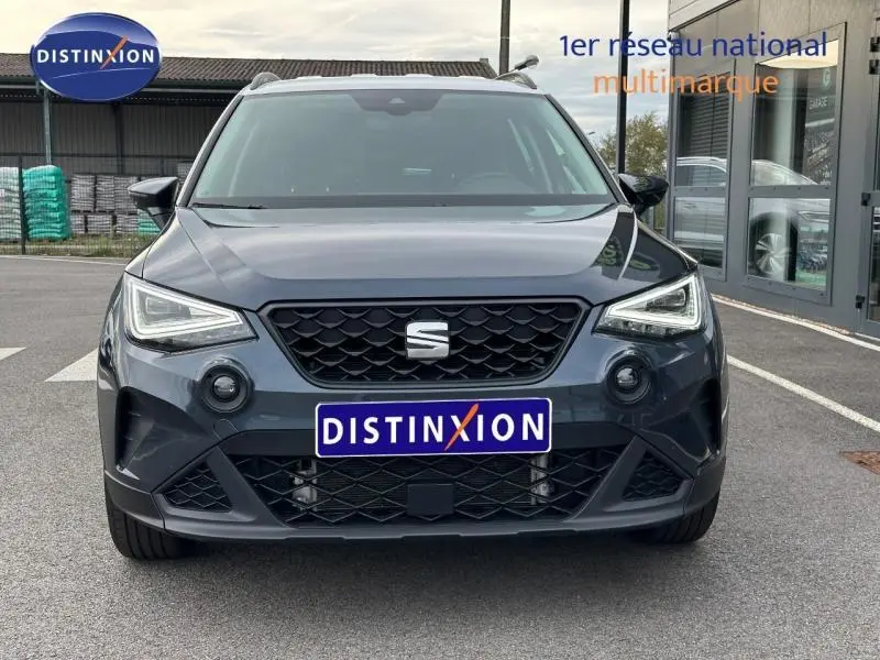 Vue frontale d'un SEAT Arona 2025 gris Magnétique Métal avec toit blanc, calandre noire et phares LED allumés.