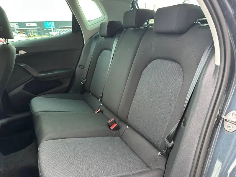 Vue intérieure côté droit des sièges arrière noirs du SEAT ARONA 2025, tissu sobre et ceintures visibles.