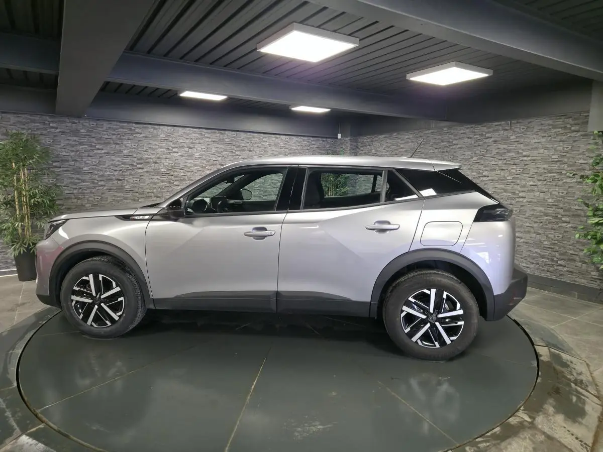 Vue de profil côté gauche d'un Peugeot 2008 gris métallisé avec jantes noires et toit noir contrasté.