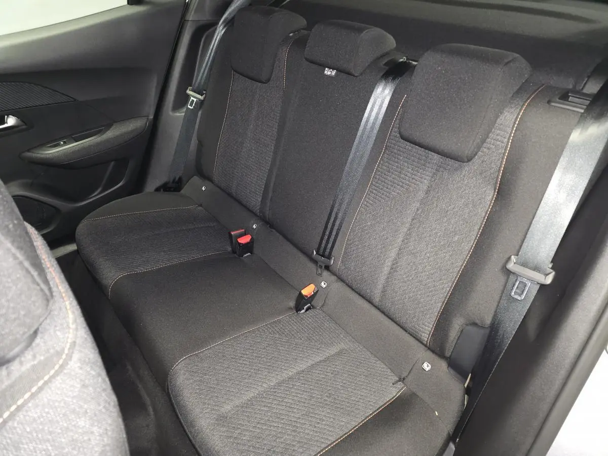 Vue intérieure de la banquette arrière en tissu gris foncé avec surpiqûres orange du Peugeot 2008 1.2i Hybrid 2025.