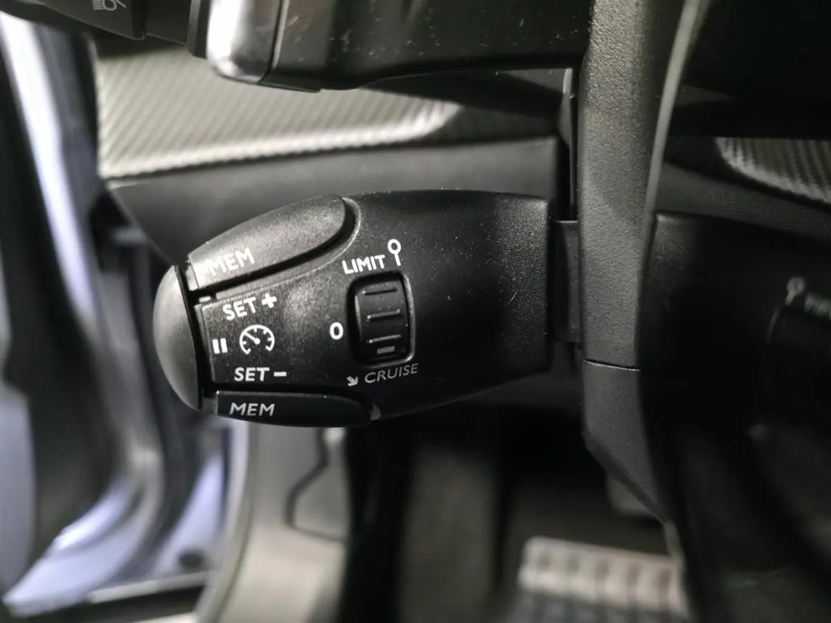 Gros plan sur la commande de régulateur de vitesse noire dans l’habitacle du Peugeot 2008 gris 2025.
