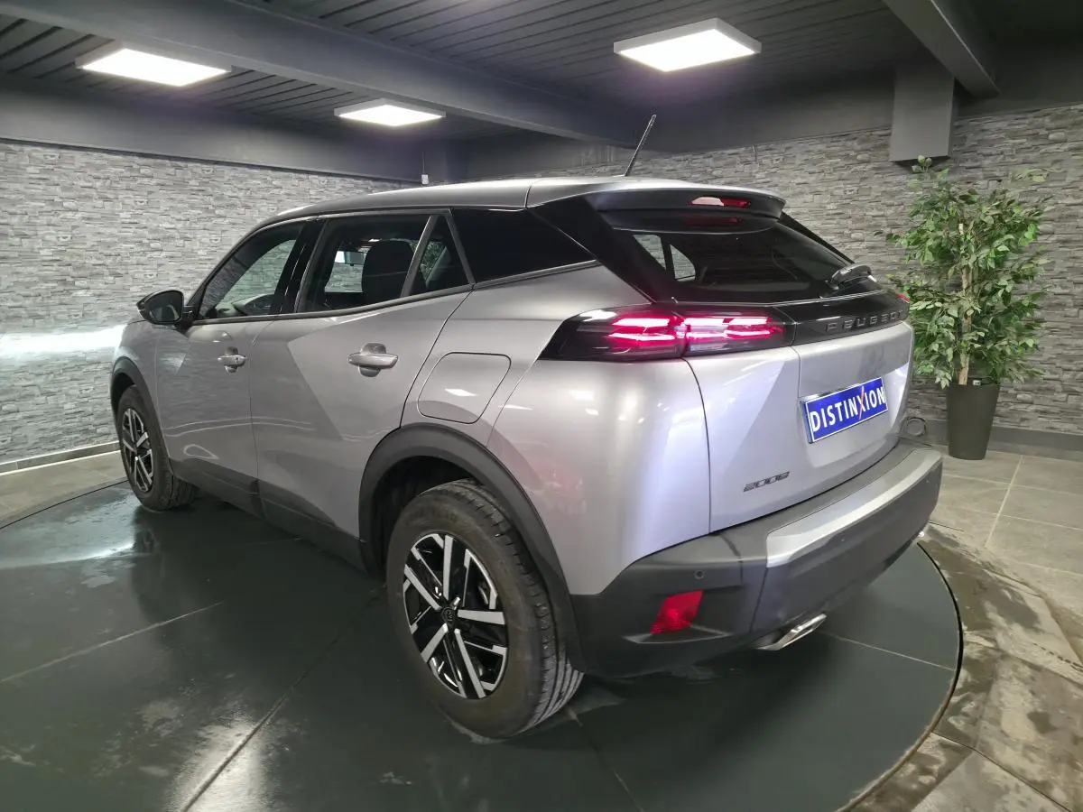 Vue 3/4 arrière droite d'un Peugeot 2008 gris métallisé avec feux arrière LED 3 griffes et jantes noires et argent.
