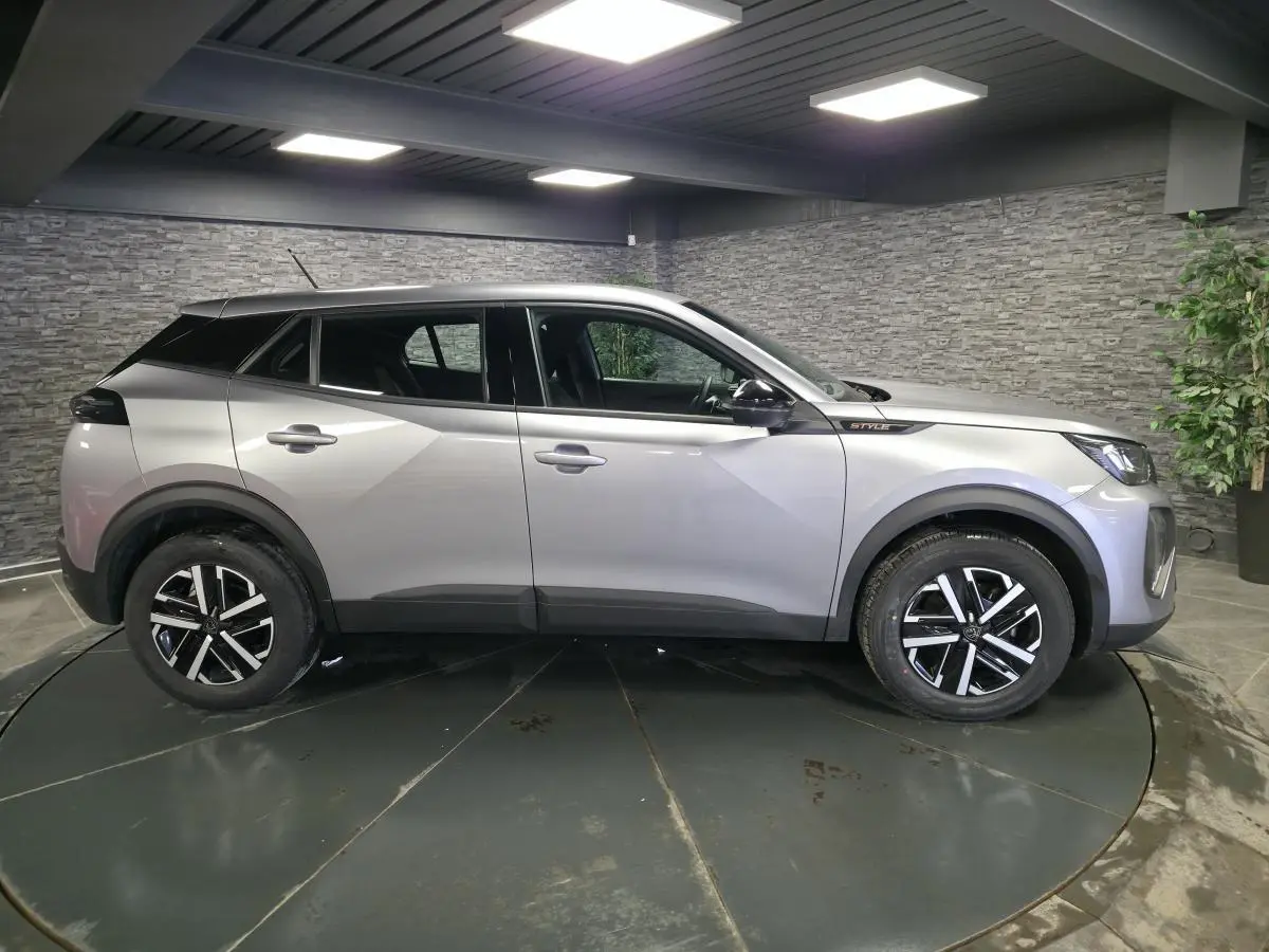 Peugeot 2008 gris métallisé vue de profil côté gauche, avec jantes noires et badge Style sur l'aile avant.