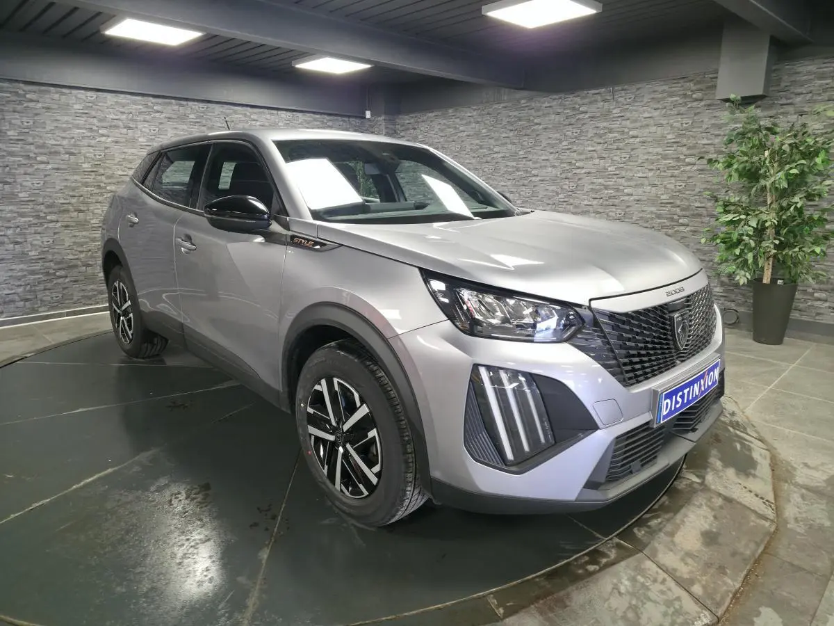 Peugeot 2008 gris métallisé vue 3/4 avant droit avec calandre noire et jantes noires et argentées.