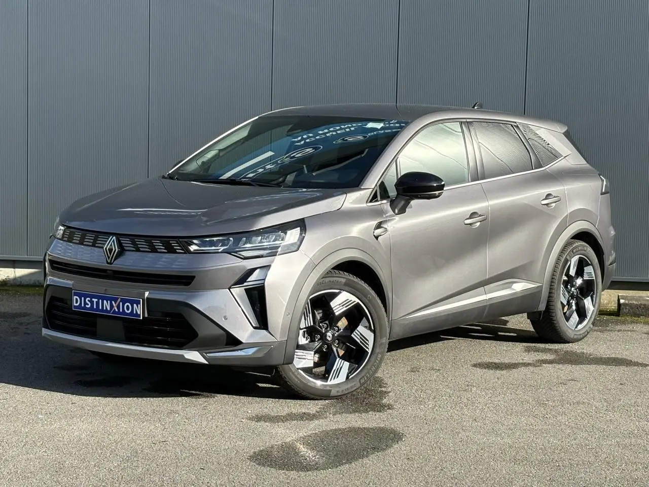 Renault Symbioz gris Cassiopée en 3/4 avant droit, avec jantes 18 pouces et rétroviseurs noirs brillants.