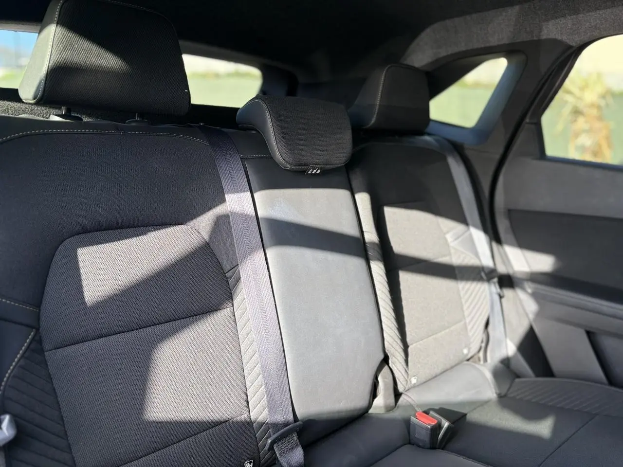 Vue intérieure de la banquette arrière en tissu gris foncé du Renault SYMBIOZ 2025 avec appuie-têtes et ceintures visibles.