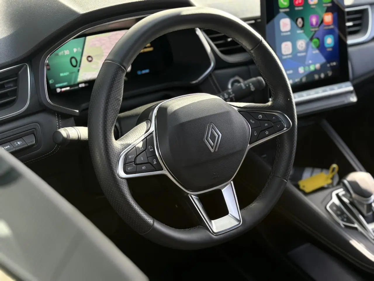 Vue rapprochée du volant noir de la Renault Symbioz 2025 avec commandes intégrées et écran tactile en arrière-plan.