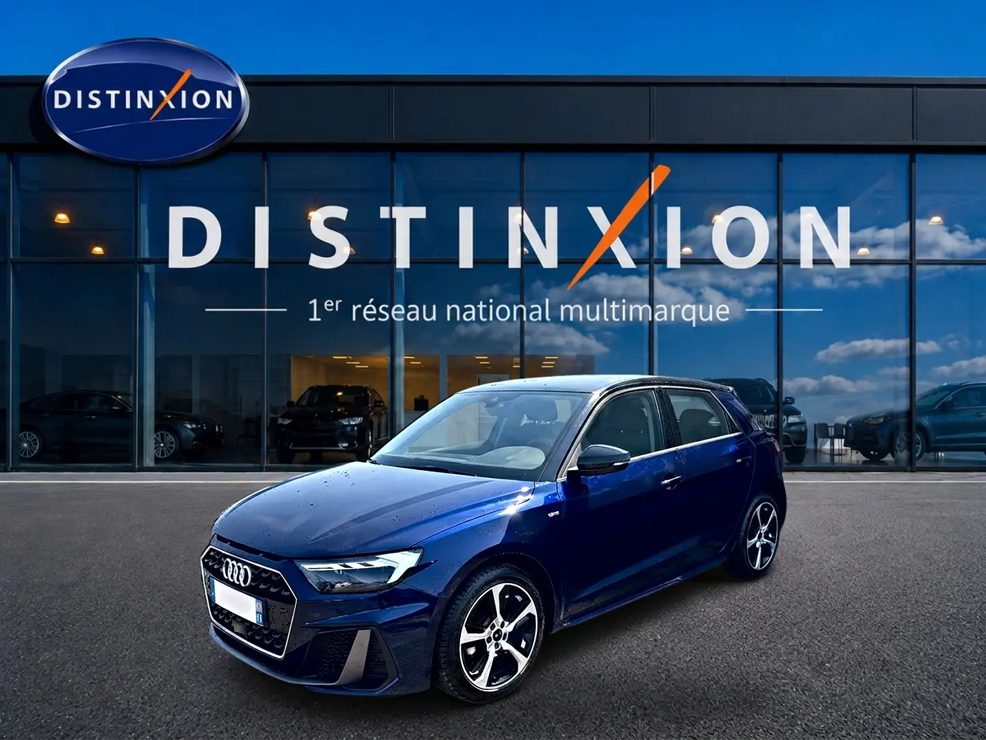 Audi A1 Sportback bleu foncé avec toit noir, vue 3/4 avant droit devant une vitrine Distinxion.