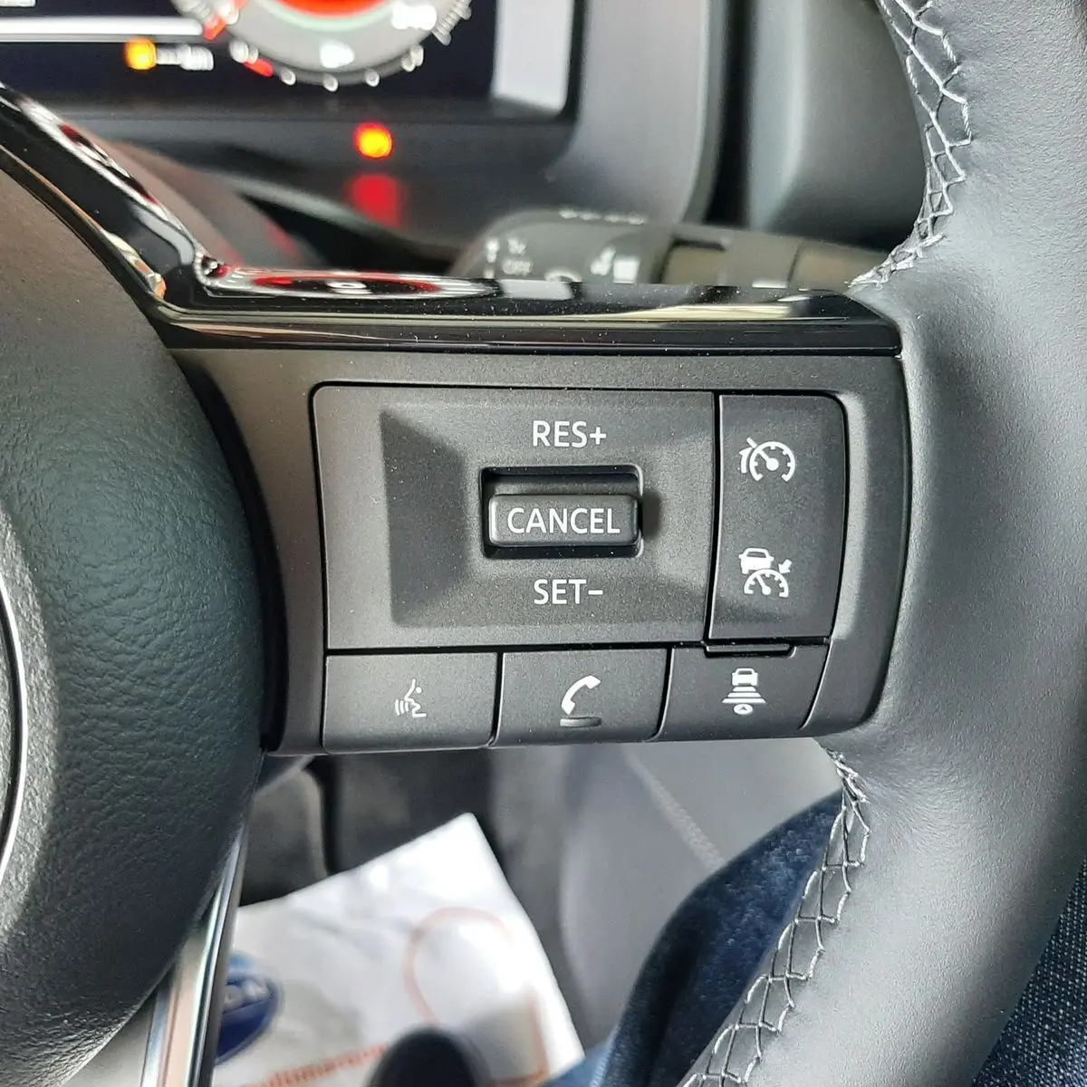 Gros plan sur les commandes au volant du Nissan Qashqai blanc lunaire 2022, version N-Connecta mild hybrid.