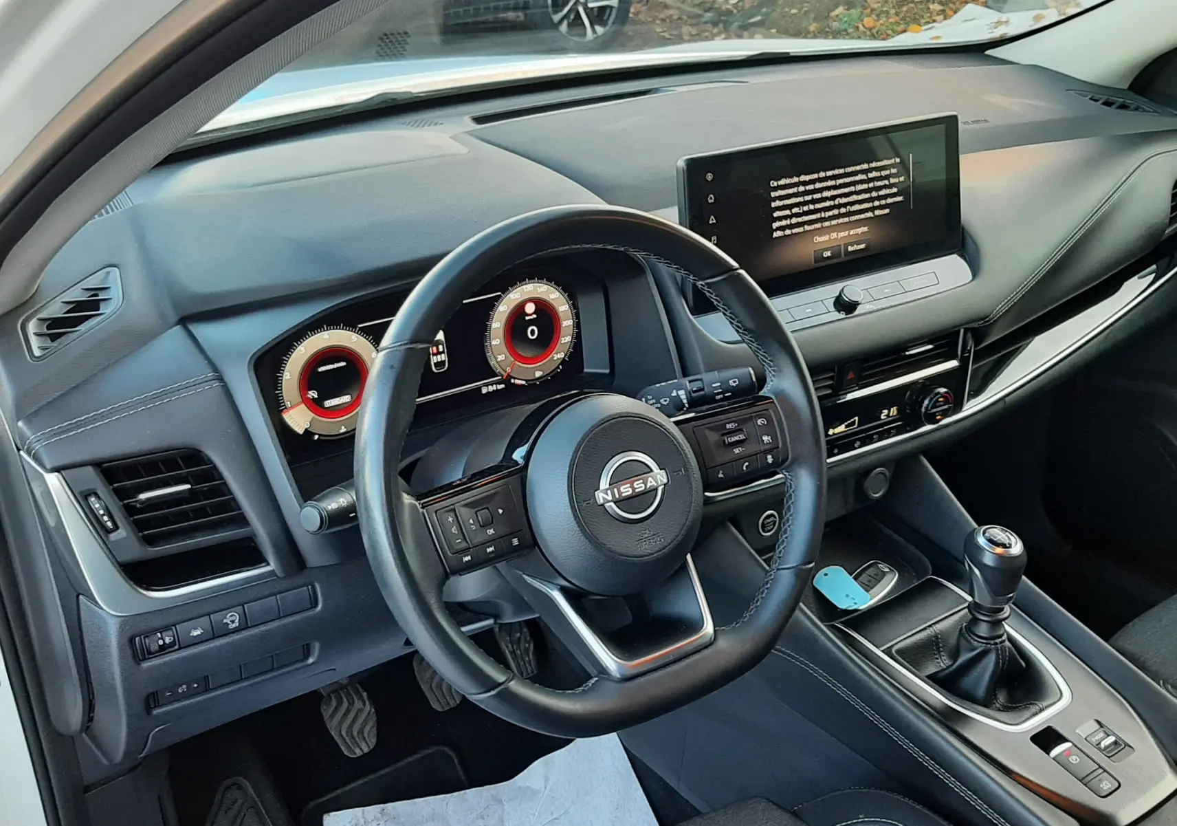 Intérieur du Nissan Qashqai blanc lunaire 2022, vue côté conducteur sur le tableau de bord et la boîte manuelle.