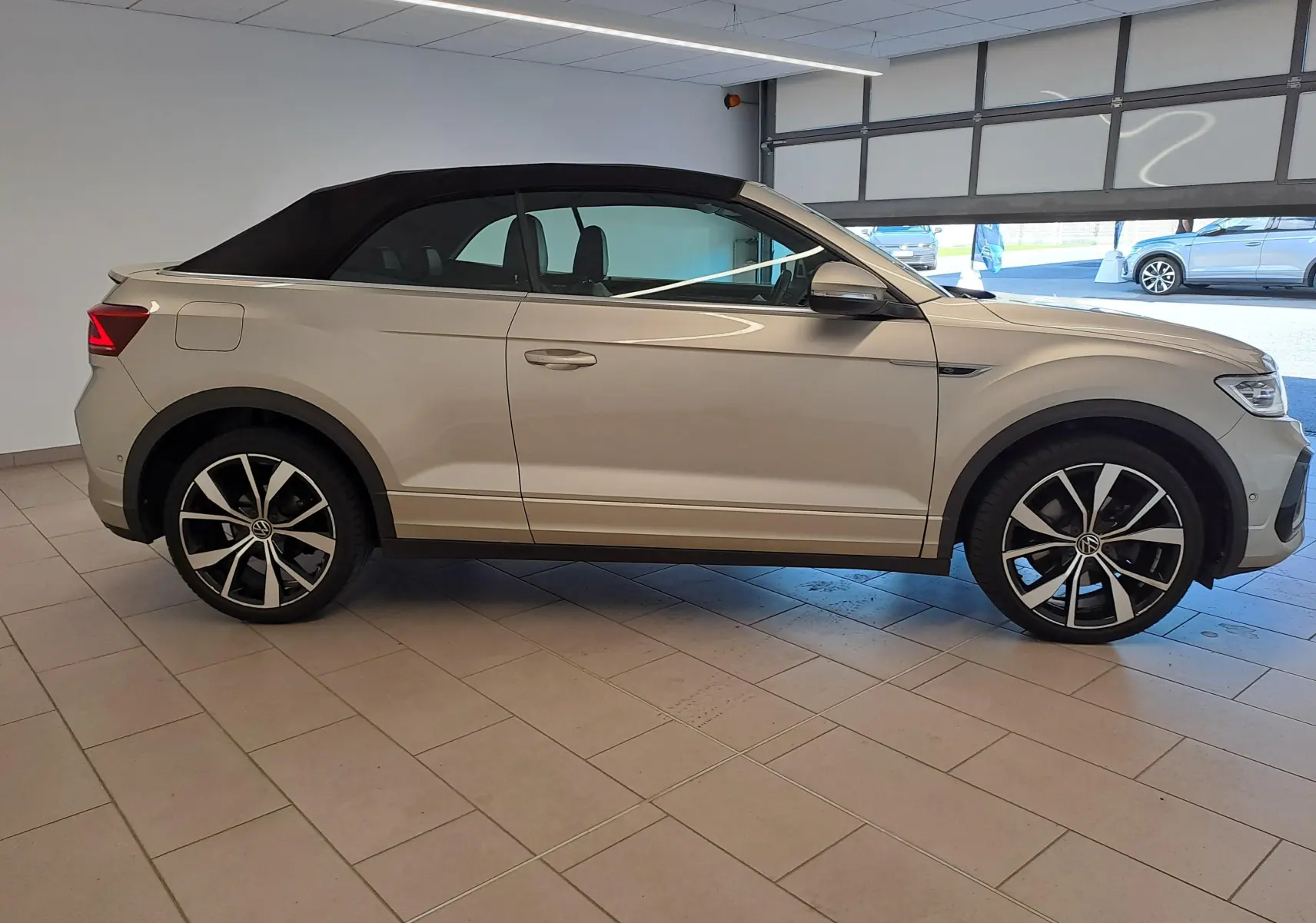 Volkswagen T-Roc Cabriolet gris ivoire vue de profil côté gauche avec capote noire et jantes alliage 19 pouces.