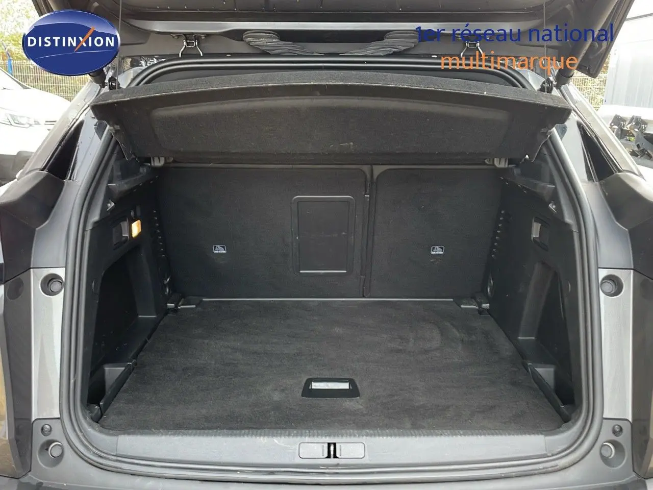 Coffre ouvert d'un Peugeot 3008 gris platinium métal, vue arrière montrant l'espace de chargement vide et propre.