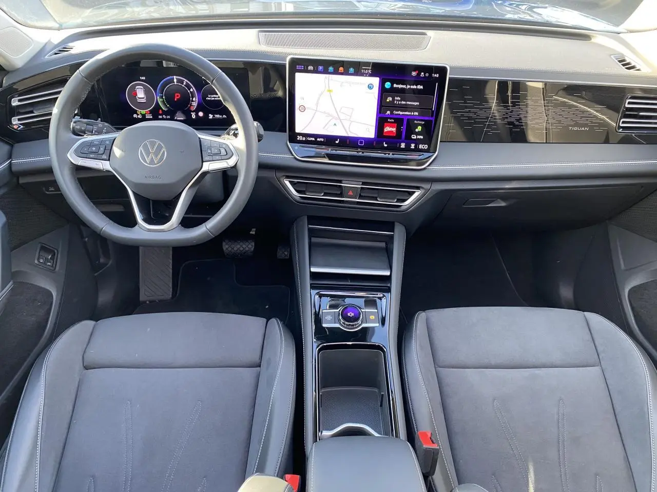 Vue intérieure avant du Volkswagen Tiguan 1.5 eHybrid 2025, tableau de bord numérique et écran tactile central visibles.