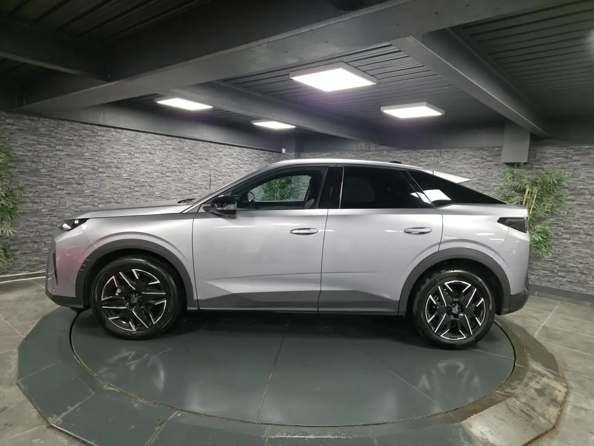Vue de profil côté gauche du Peugeot 3008 gris métallisé 2025 avec jantes alliage noires et toit noir.