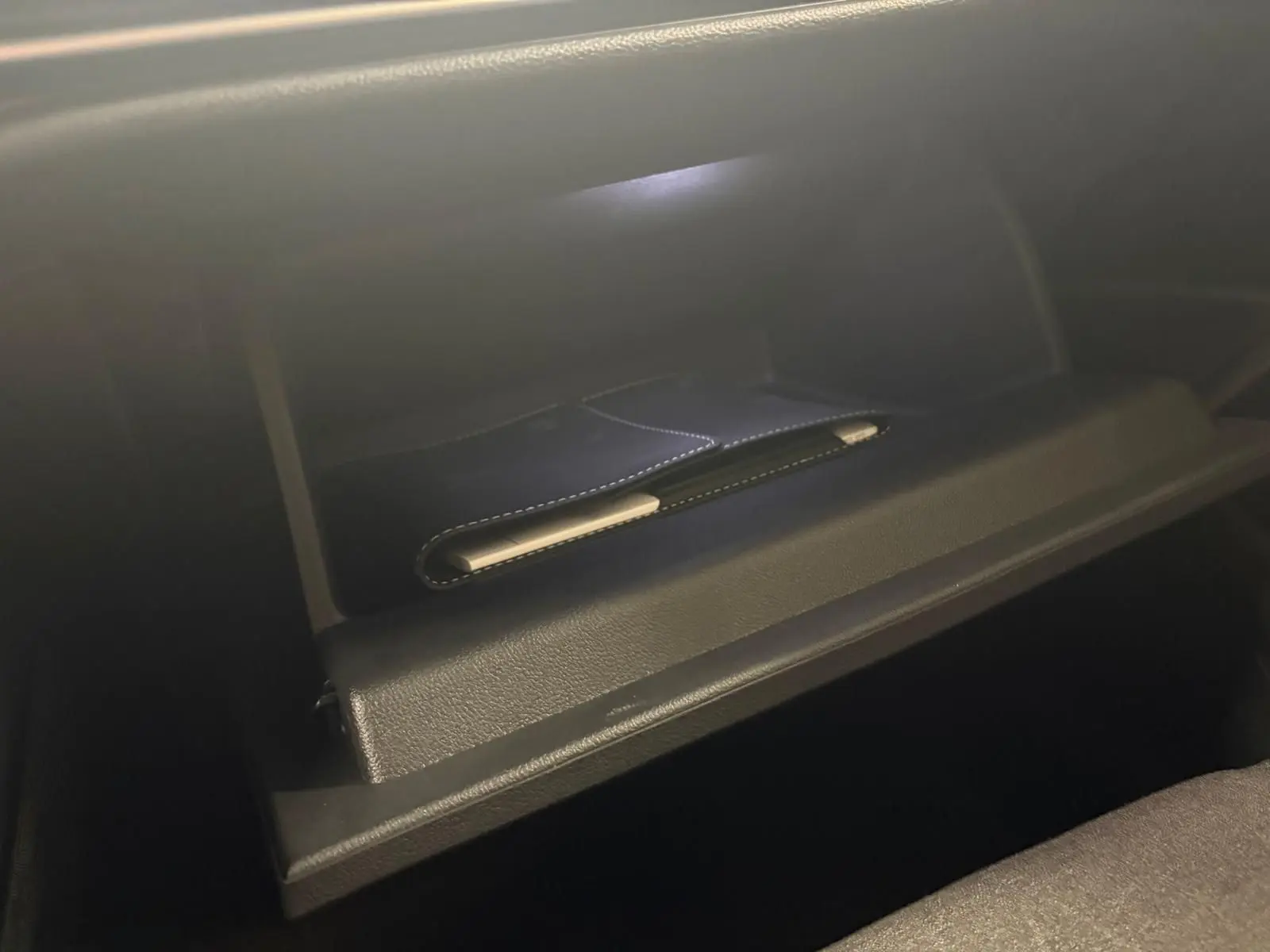 Boîte à gants ouverte de la Volkswagen Golf 1.5 eTSI 116 DSG7 Bleu Anémone, intérieur noir avec surpiqûres.