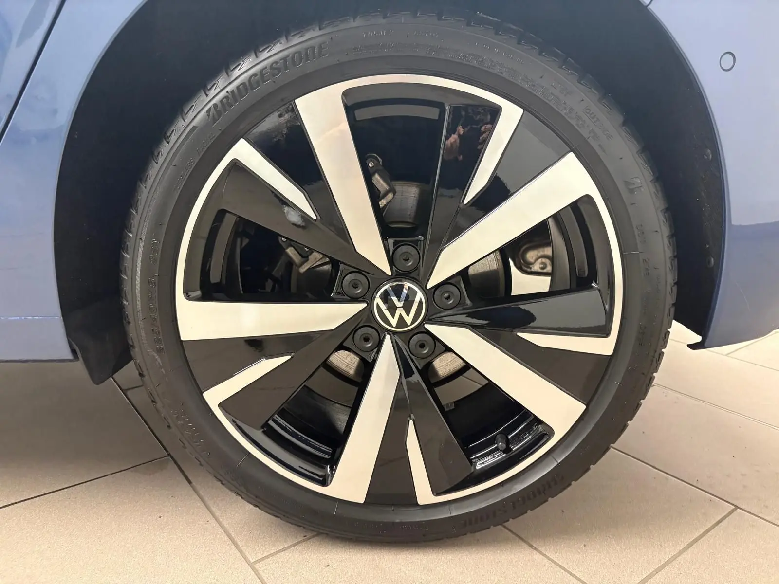 Gros plan sur la jante alliage 18'' Catania bicolore noir et argent d'une Volkswagen Golf Bleu Anémone.
