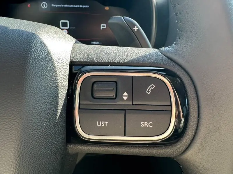 Gros plan sur les commandes au volant droit du Citroën C5 Aircross 2025, boutons noirs avec contour chromé.
