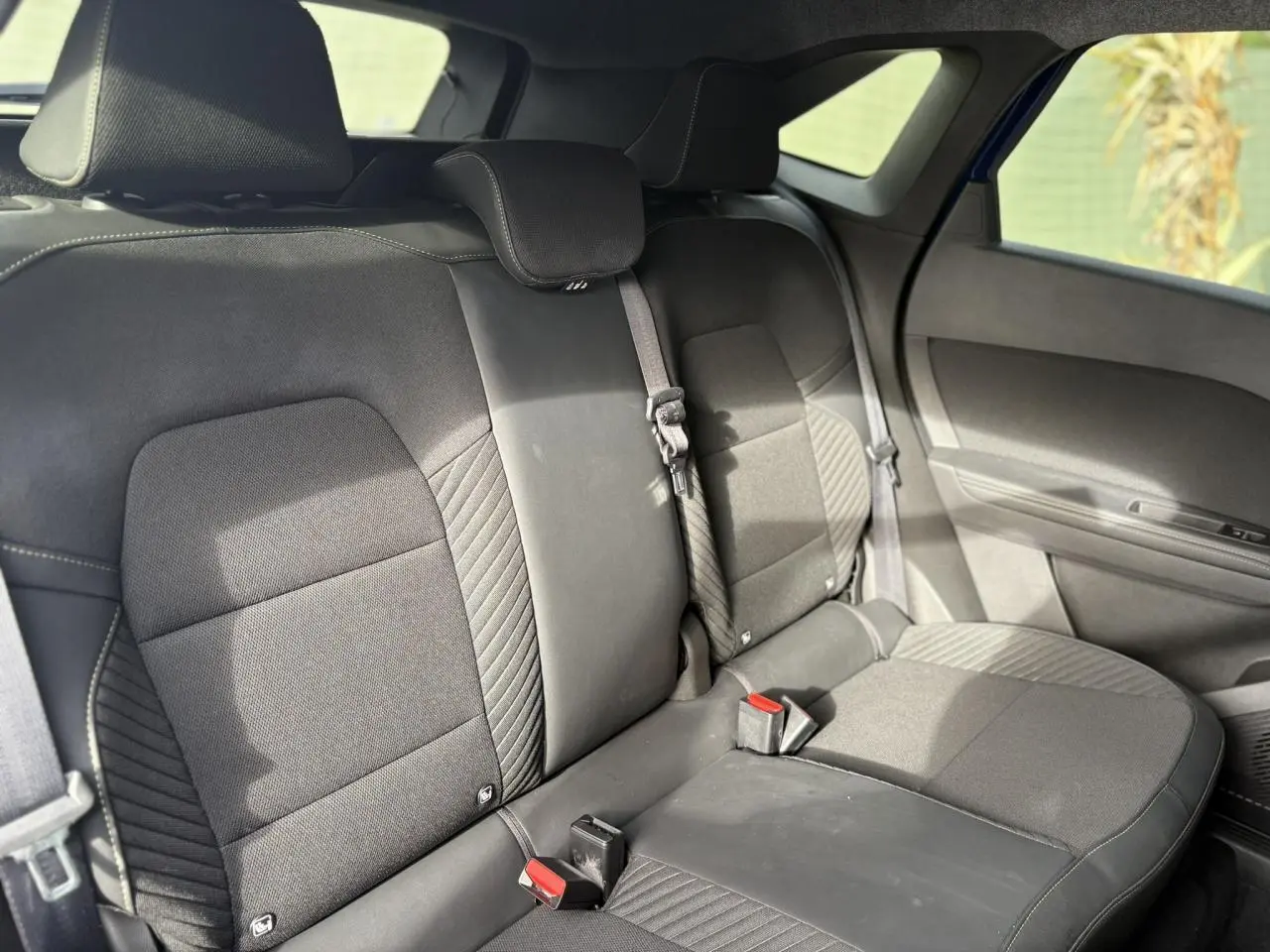 Vue intérieure montrant la banquette arrière en tissu noir avec appuie-têtes et ceinture de sécurité sur Renault Symbioz Bleu Iron.