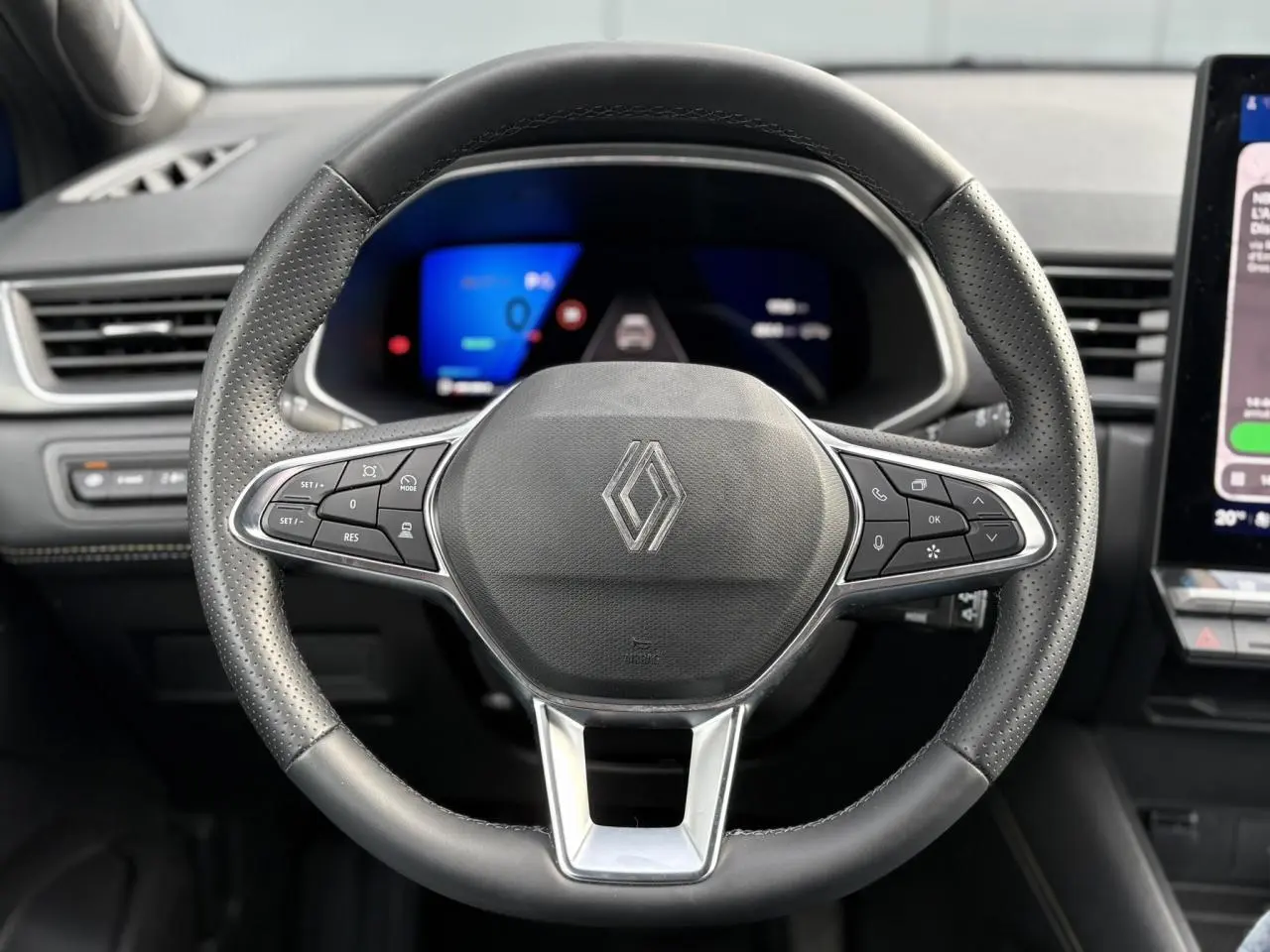 Vue rapprochée du volant noir perforé de la Renault SYMBIOZ 2025 avec commandes intégrées et tableau de bord numérique.
